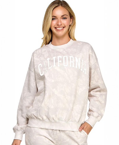 Woman wearing a light beige camo sweatshirt with 'California' printed on it against a white background