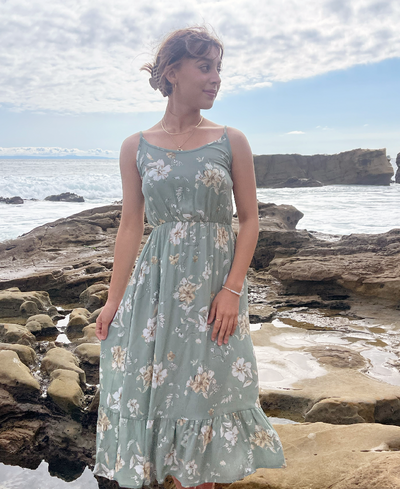 Girl wearing green tropical tier dress with ruffle at bottom and pockets 