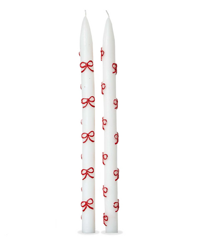 Two white candles with red bow patterns on a white background