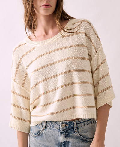 Woman wearing a beige and brown striped sweater with blue jeans on a white background