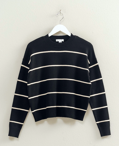 Black and white striped sweater on a hanger against a plain background