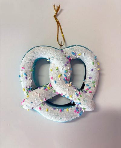 Decorative pretzel ornament with colorful sprinkles on a plain background
