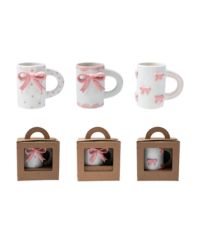 Three white mugs with pink bows in cardboard packaging on a white background