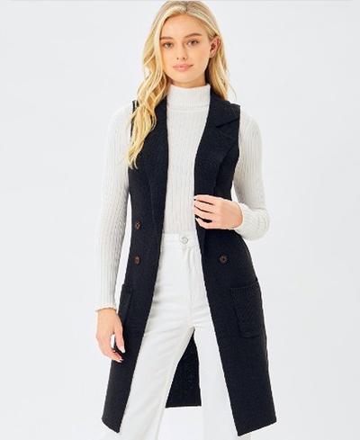 Woman wearing a long black vest over a white outfit on a white background