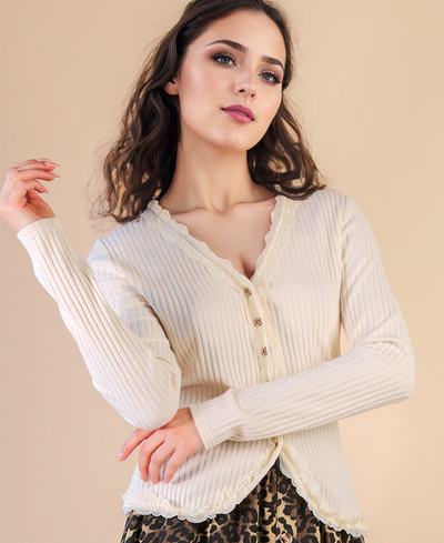 Woman wearing a cream ribbed cardigan against a beige background