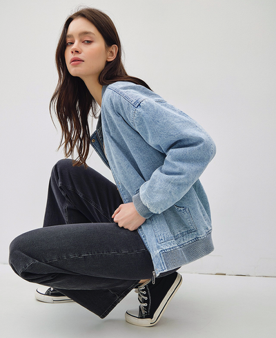 Person wearing a light blue denim jacket and dark jeans on a white background