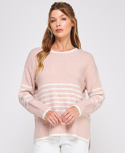 Woman wearing a light pink sweater with white stripes on a plain background