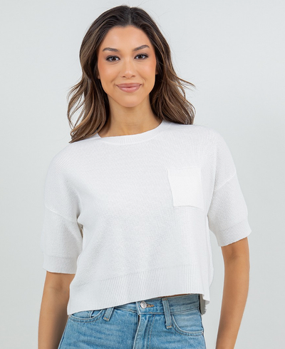 Woman wearing a white sweater and blue jeans on a plain background