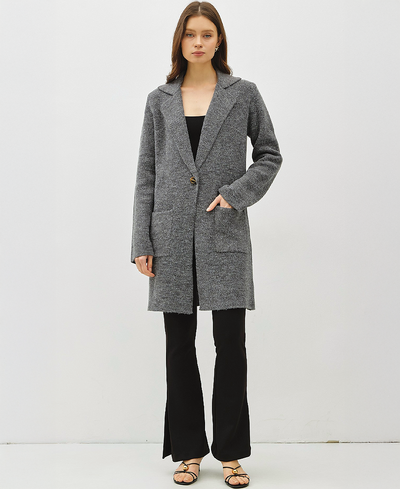 Woman wearing a gray coat over a black outfit on a white background