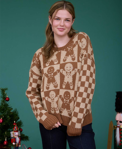 Woman wearing a patterned sweater with gingerbread men design, standing against a teal background with Christmas decorations.