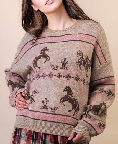 Person wearing a sweater with horse patterns on a beige background