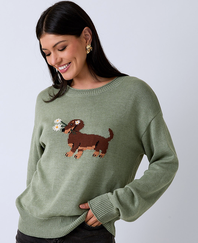 Woman wearing a green sweater with a dachshund design on a plain background