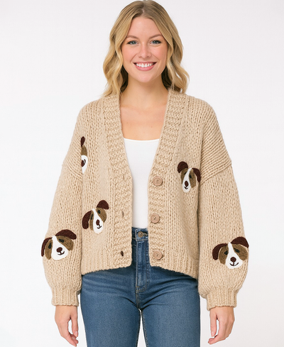 Woman wearing a beige cardigan with dog face patterns on a white background