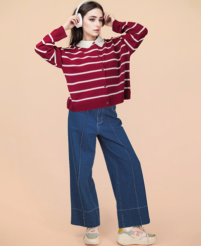 Woman wearing a red and white striped sweater and blue jeans on a beige background
