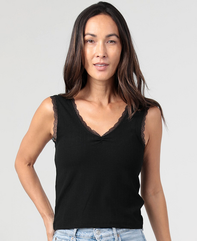 Woman wearing a black sleeveless top with lace details on a gray background