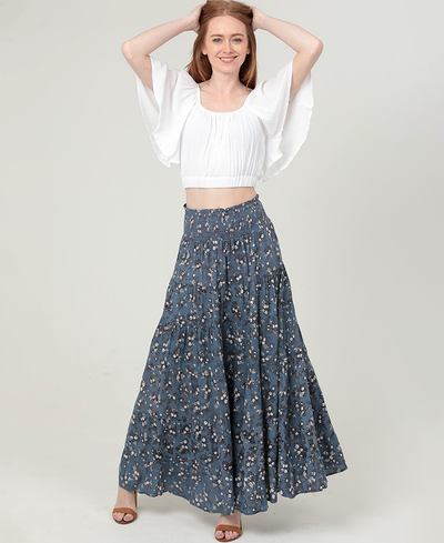 Woman wearing a white blouse and blue floral skirt on a plain background