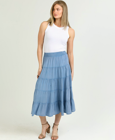Woman wearing a white top and blue tiered skirt on a white background