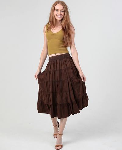 Woman wearing a brown tiered skirt and mustard top on a white background