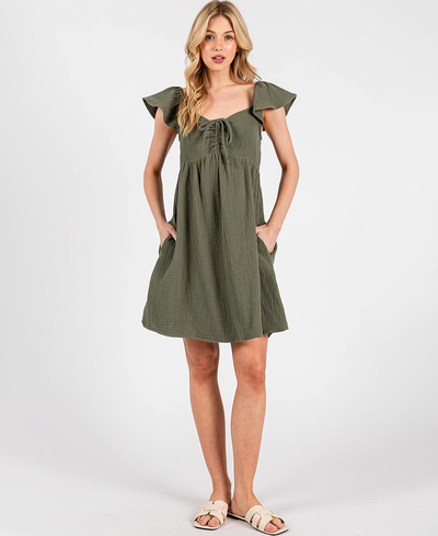 Woman wearing a green dress with ruffled sleeves on a white background