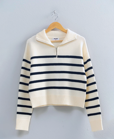 Striped sweater on a hanger against a light gray background