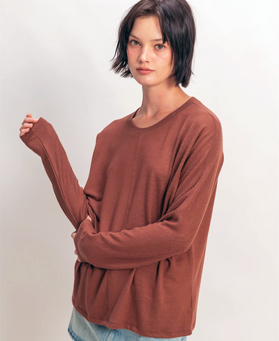 Woman wearing a brown long-sleeve shirt against a plain background