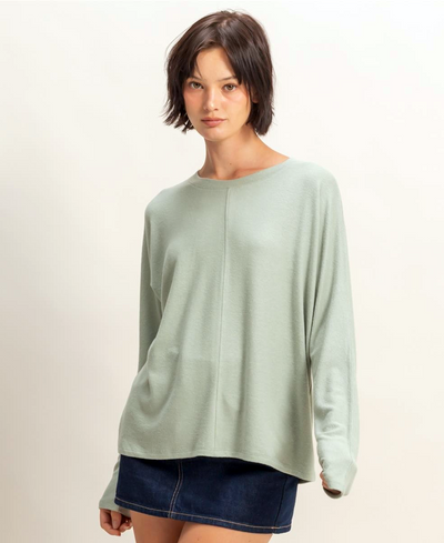 Woman wearing a light green long-sleeve top on a plain background