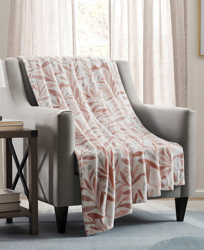 Floral patterned blanket draped over a gray armchair in a living room setting.