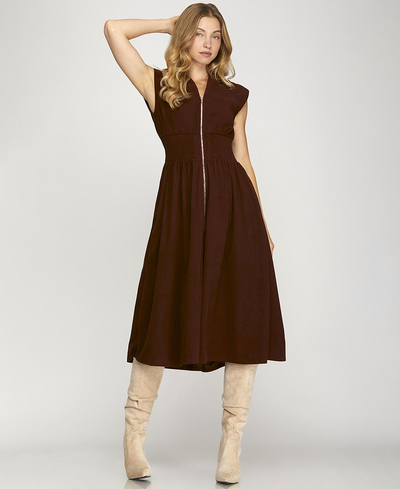 Woman wearing a brown dress with beige knee-high boots on a white background