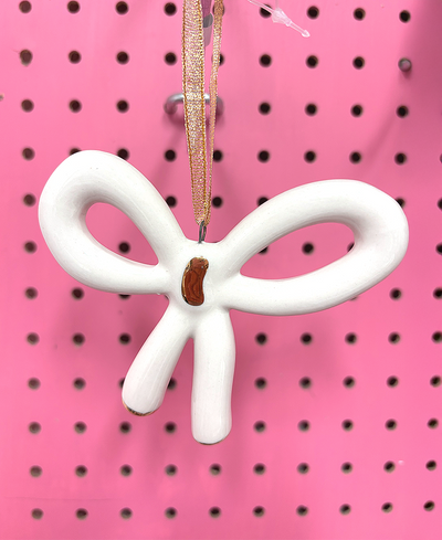 White bow-shaped ornament on a pink pegboard background