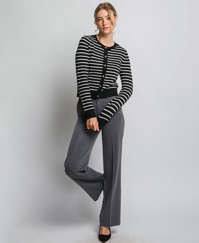 Woman wearing a black and white striped cardigan with gray pants on a plain background