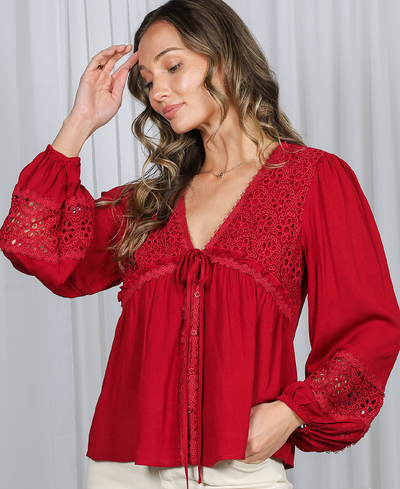 Woman wearing a red blouse with lace details against a white background