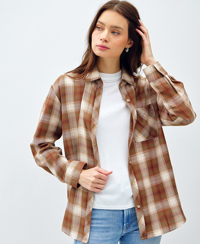 Woman wearing a plaid shirt over a white top on a light gray background