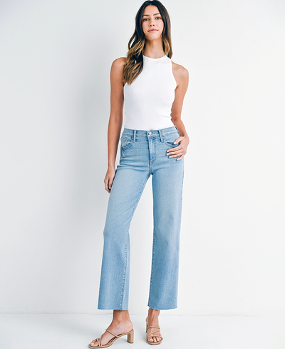 Woman wearing light blue jeans and a white top on a white background