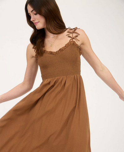 Woman wearing a brown dress with bow details on a white background