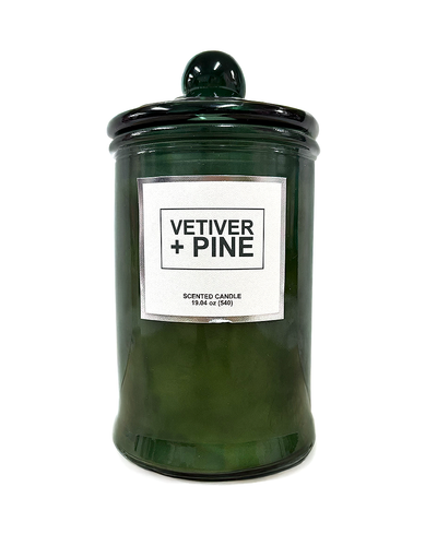 Green candle jar with a label reading 'Vetiver + Pine' on a white background