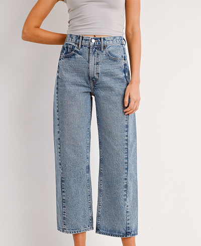 Person wearing light blue jeans on a plain background