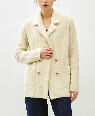 Woman wearing a cream-colored coat with gold buttons on a white background