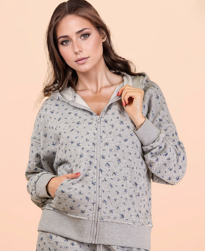 Woman wearing a gray floral hoodie against a beige background