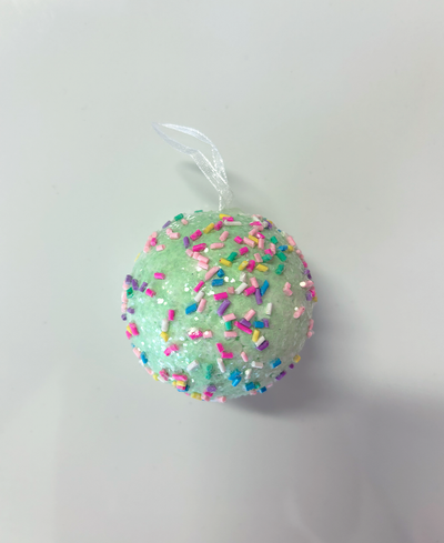 Green ball ornament with colorful sprinkles on a white background