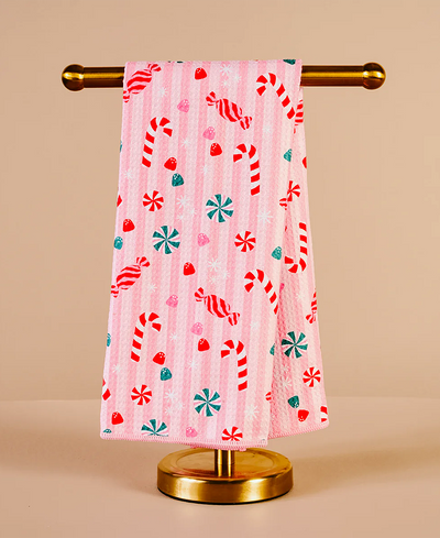 Pink towel with candy cane pattern on a gold towel rack against a beige background