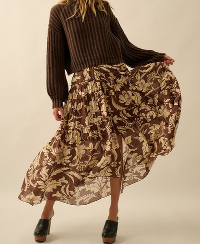 Person wearing a brown ribbed sweater and floral skirt on a beige background