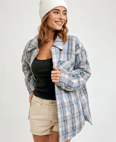 Woman wearing a plaid shirt over a black top and beige shorts on a white background