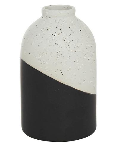Vase that is half black and half white with black splatters of paint.